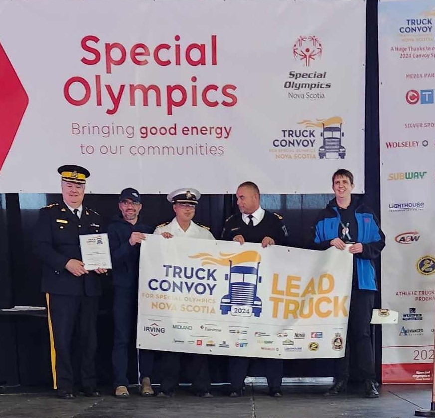 Convoy lead truck driver, Edwin MacDonald (2nd from left) is presented with the Lead Truck banner at the 2024 Special Olympics Truck Convoy in Halifax.