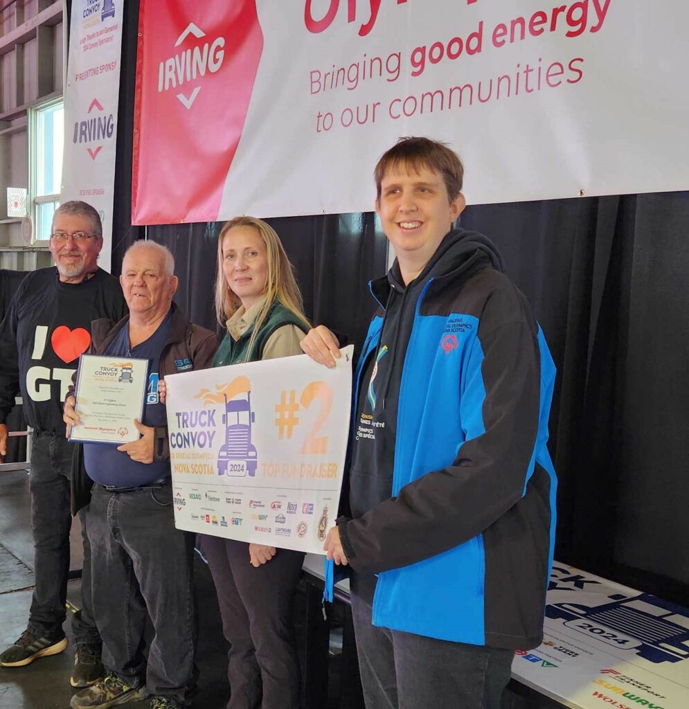 Truckers presented with the a banner and a certificate at stage (group photo of four)