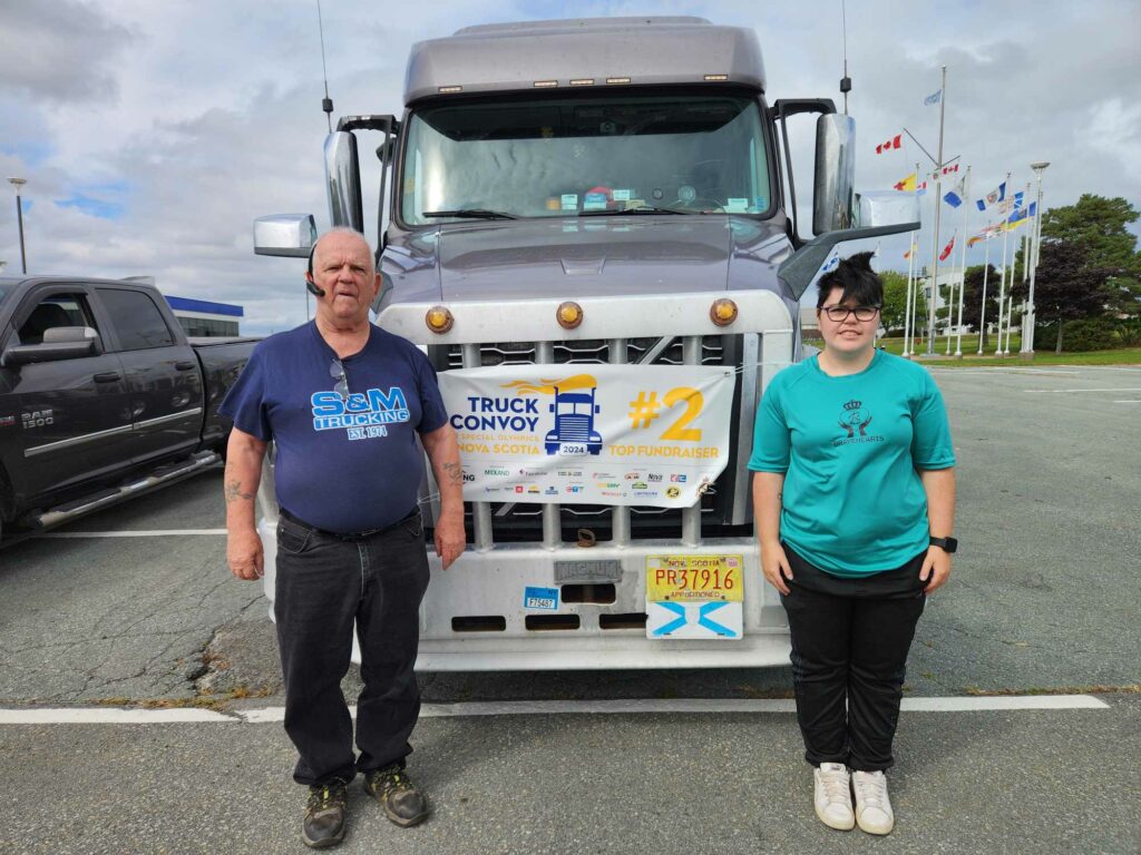 Convoy driver, Harold Varbeff is flanked by Special Olympics athlete, Skylynn Johnson Lydaird.