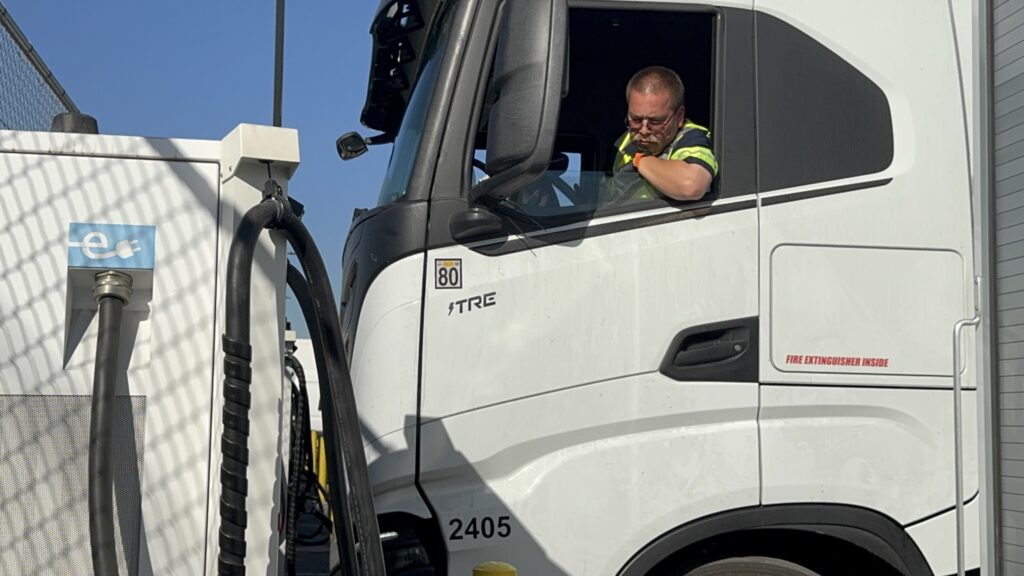 driver parking in Nikola EV truck near a charger