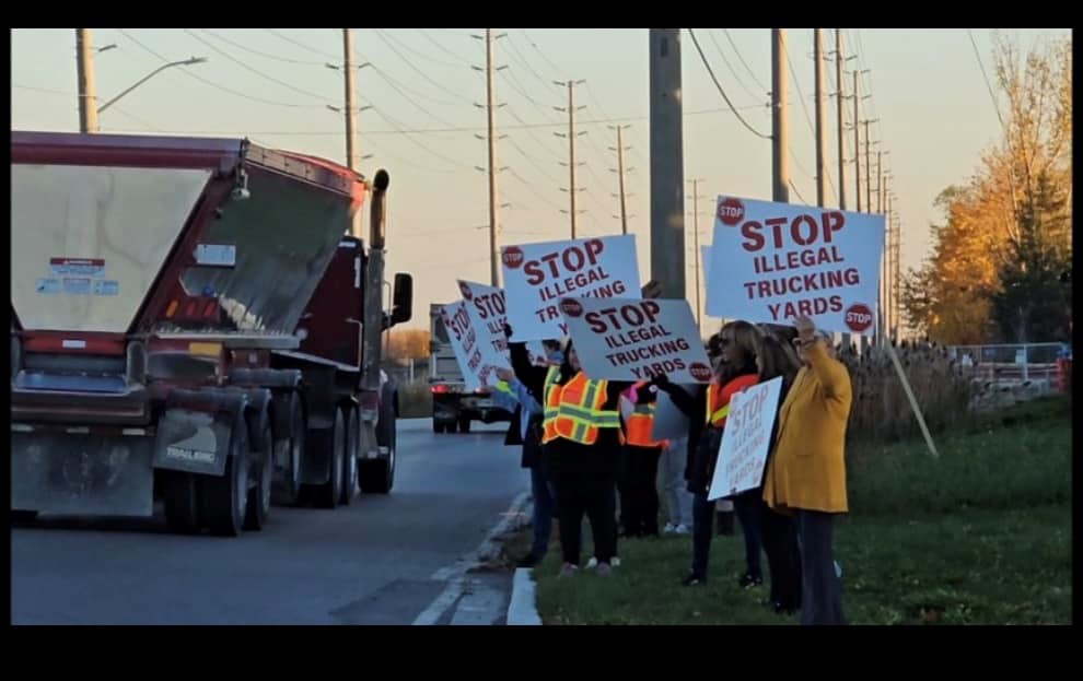 People on a sidewalk protesting against illegal truck yards.