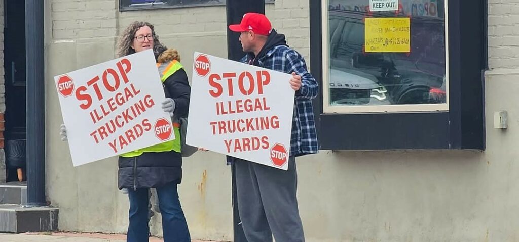 Two people on sidewalk protesting against illegal truck yards in Caledon